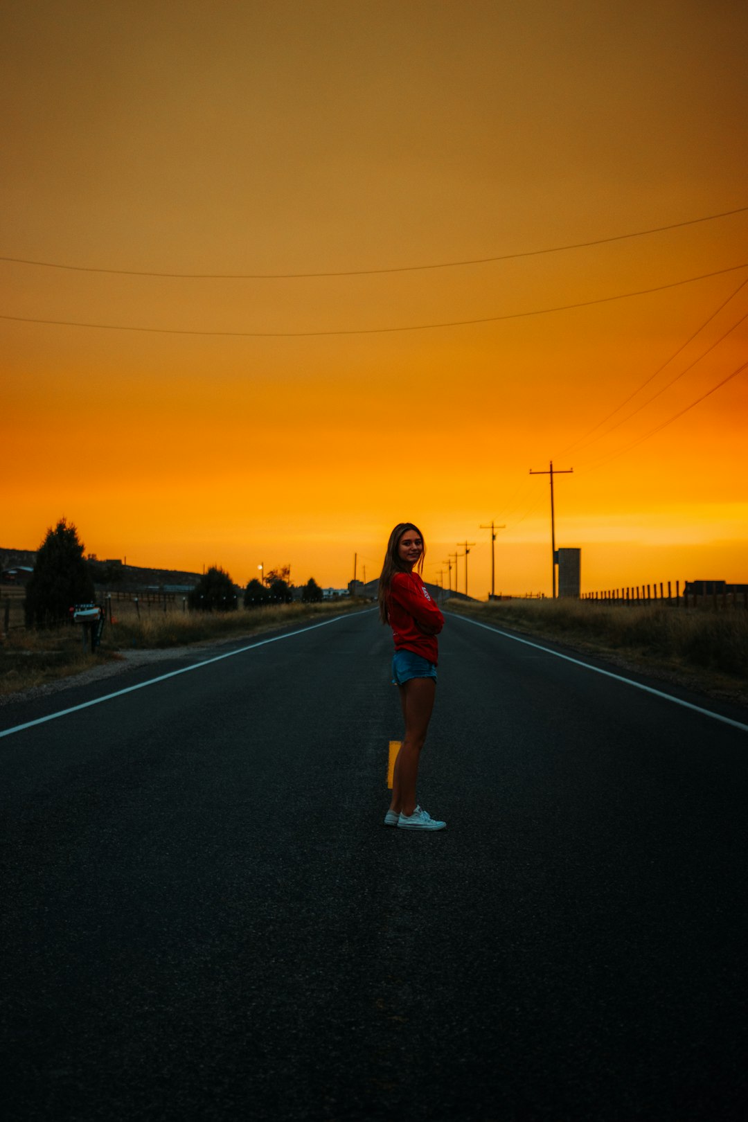 woman in red and blue plaid shirt standing on road during sunset