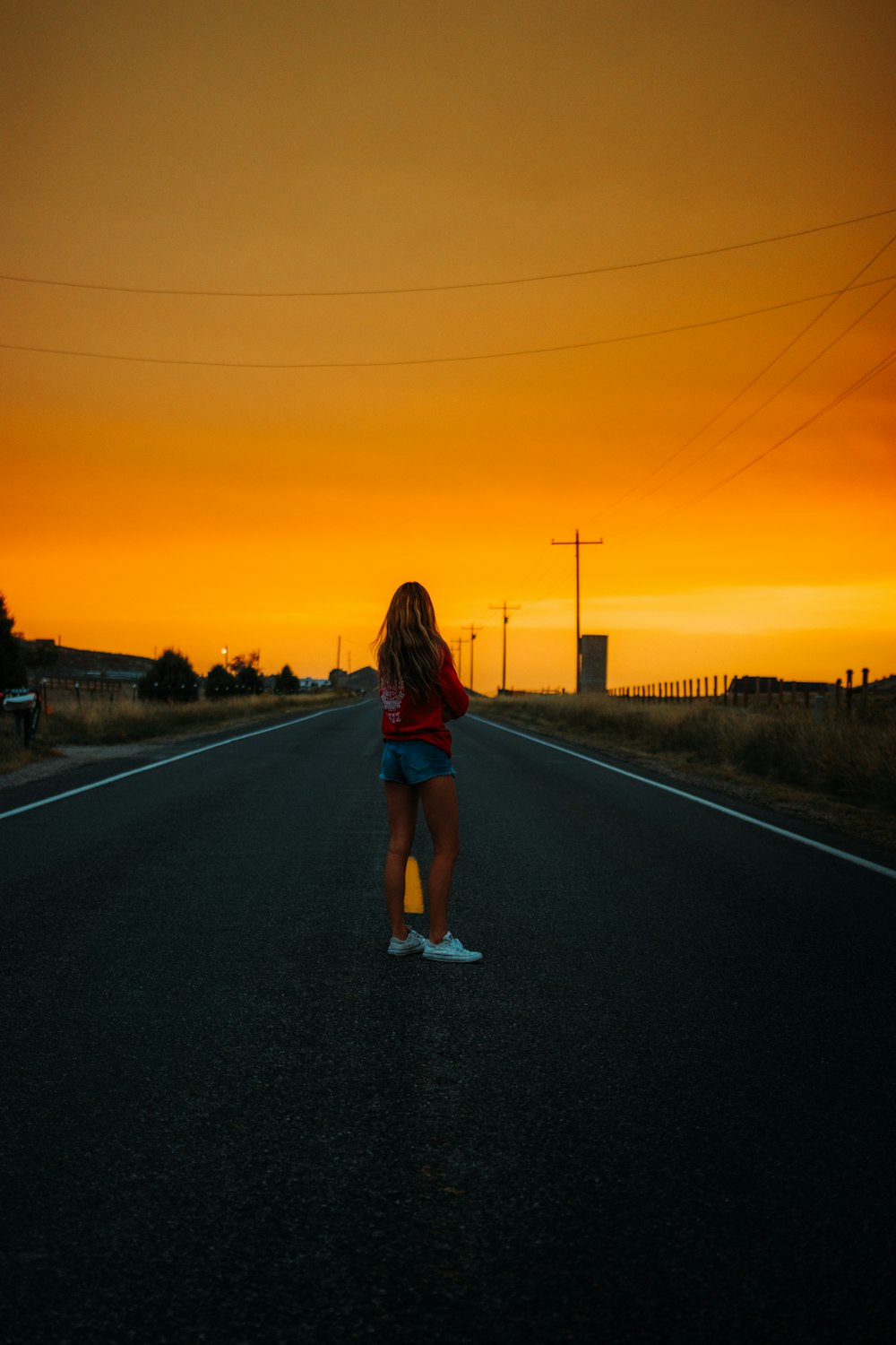woman in red shirt standing on road during sunset