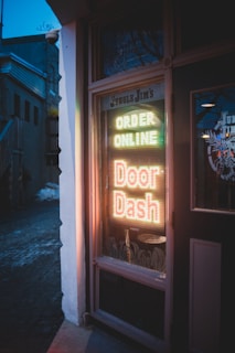 brown wooden door with red and yellow neon sign