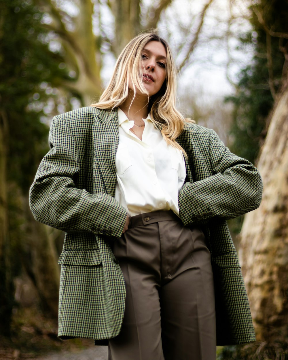 Mujer en blazer de lunares gris y blanco de pie y sonriendo