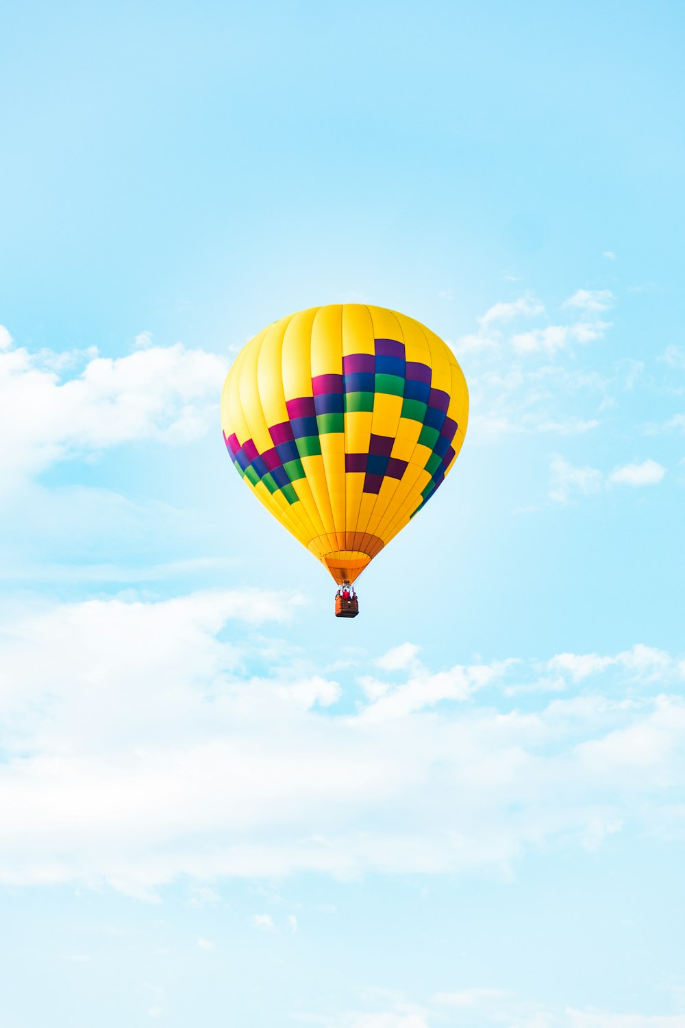 yellow blue and red hot air balloon in mid air under blue sky during daytime
