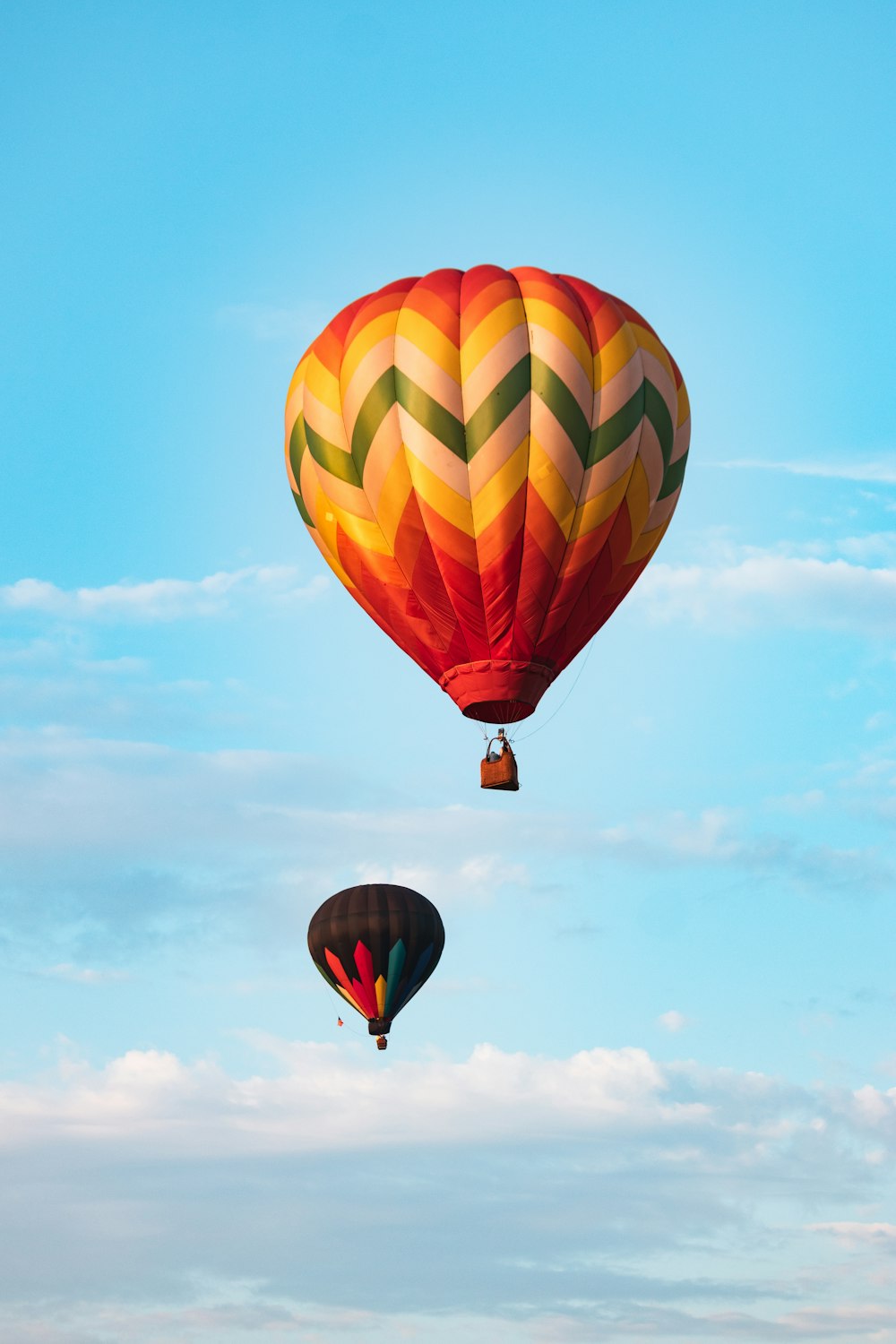 Montgolfière verte, jaune et rouge dans les airs sous le ciel bleu pendant la journée