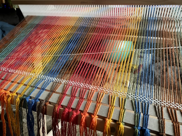 Close-up of colorful woven tapestry threads on a loom.