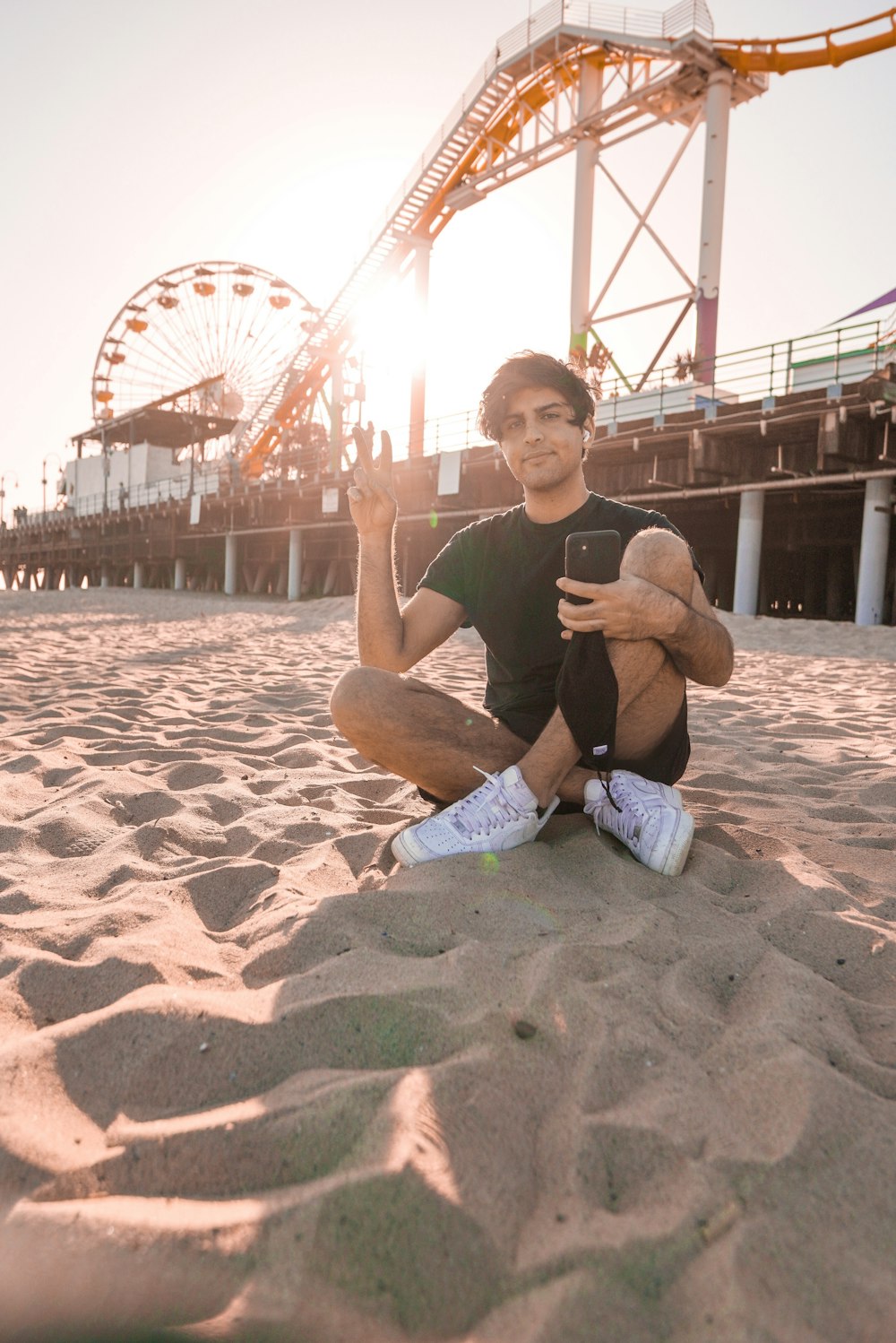 man in black crew neck t-shirt sitting on brown sand during daytime