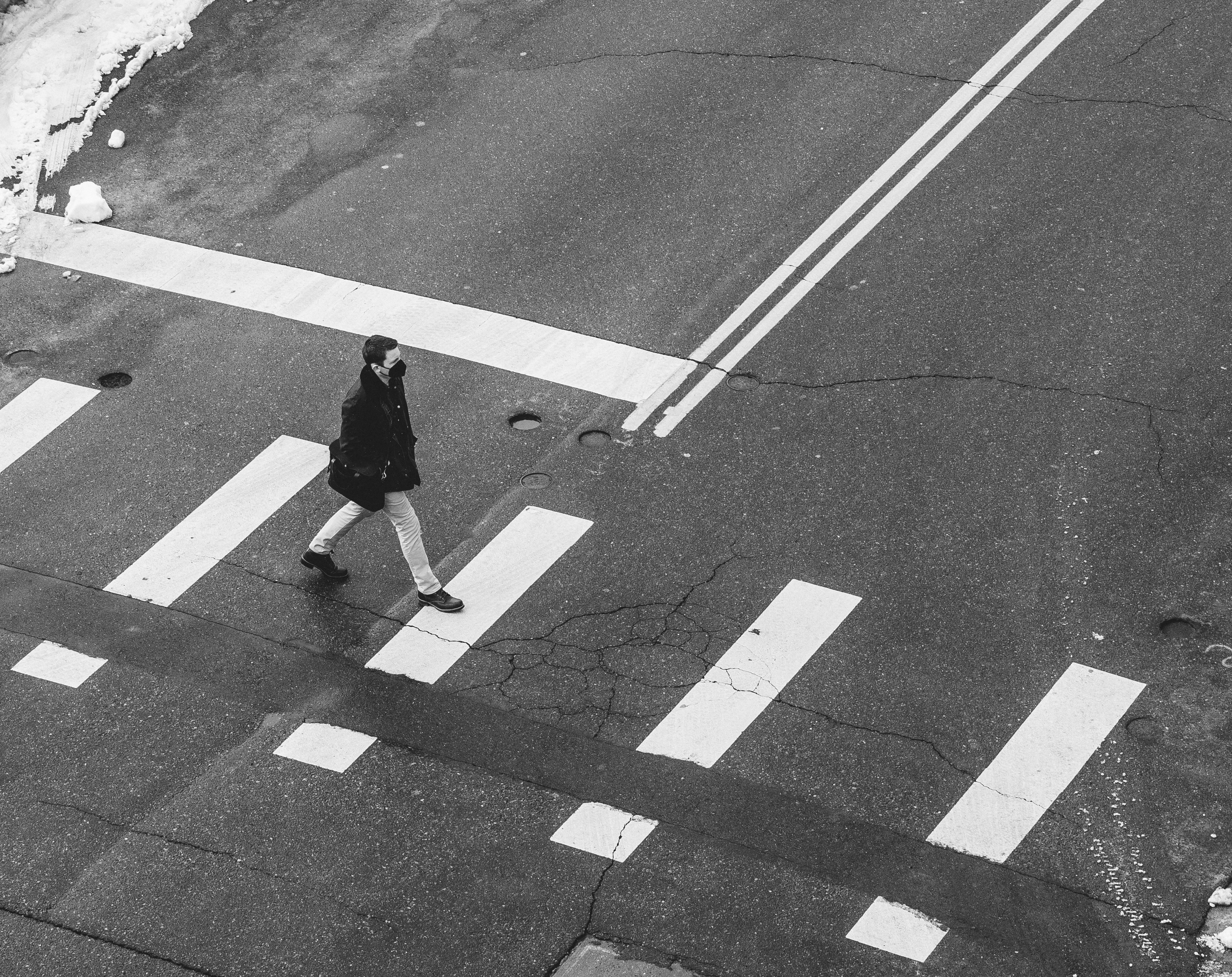 grayscale photo of woman walking on pedestrian lane