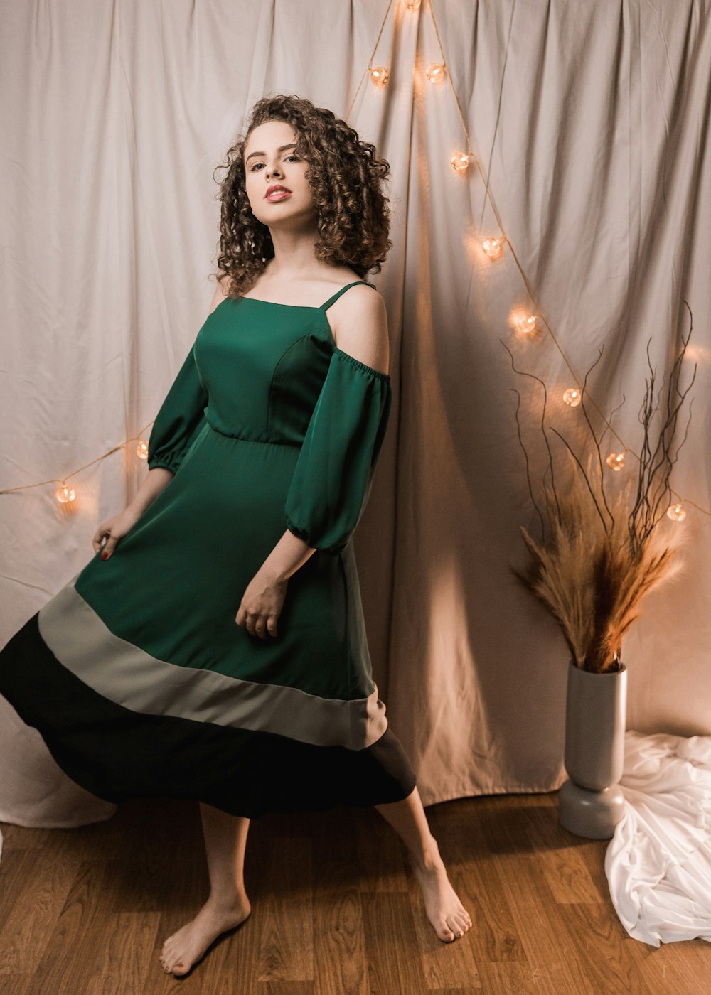 woman in green and black dress standing beside brown and white floral curtain