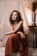woman in red sleeveless dress sitting on brown wooden chair