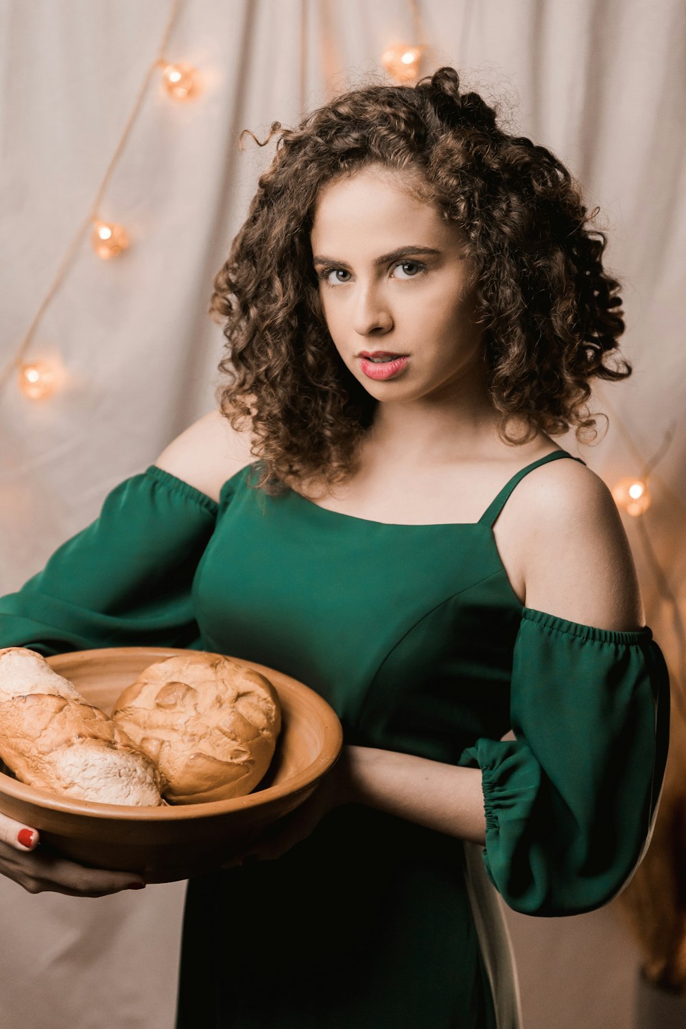 woman in green spaghetti strap top holding brown wooden bowl