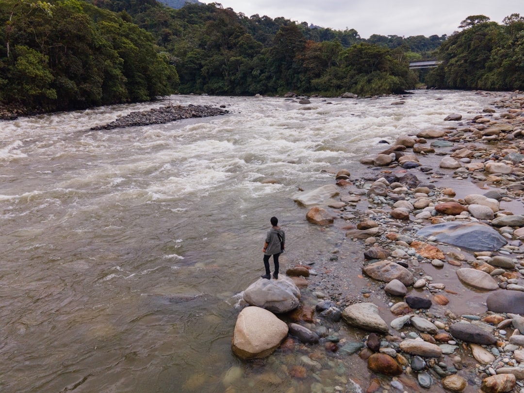 person in black jacket standing on rocky river during daytime