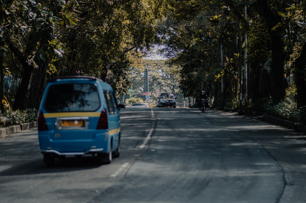 blue car on road near trees during daytime