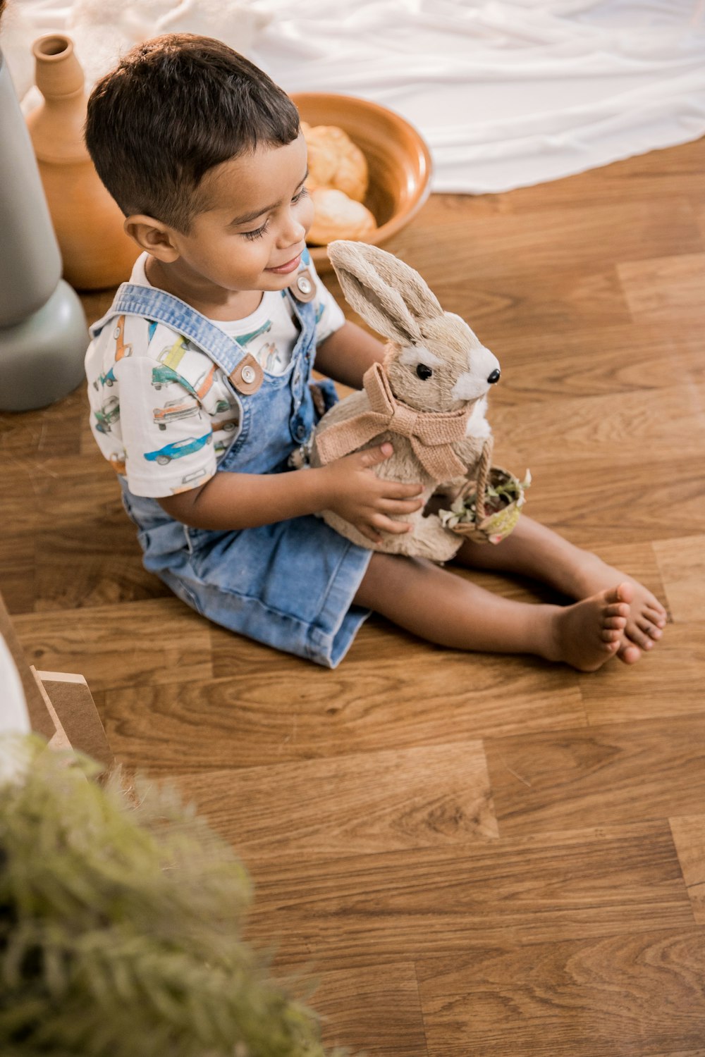 a little boy sitting on the floor holding a stuffed animal