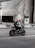 A happy motorcyclist wearing a helmet, smiling with a city street in the background.
