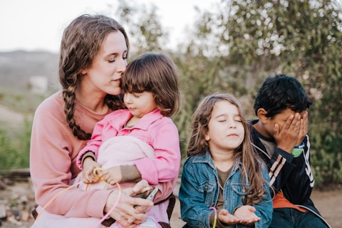 woman in blue denim jacket carrying girl in pink jacket during daytime