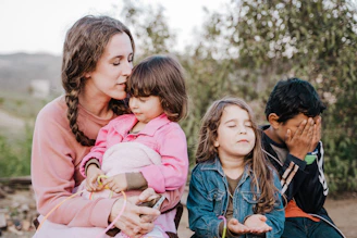 woman in blue denim jacket carrying girl in pink jacket during daytime