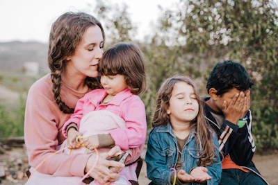 woman in blue denim jacket carrying girl in pink jacket during daytime