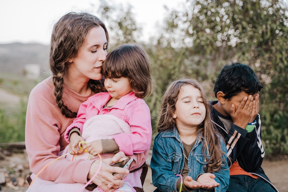 woman in blue denim jacket carrying girl in pink jacket during daytime