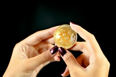 gold round coin on persons hand