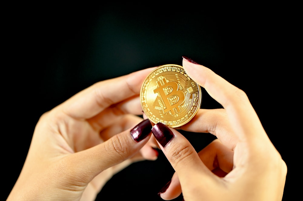 gold round coin on persons hand