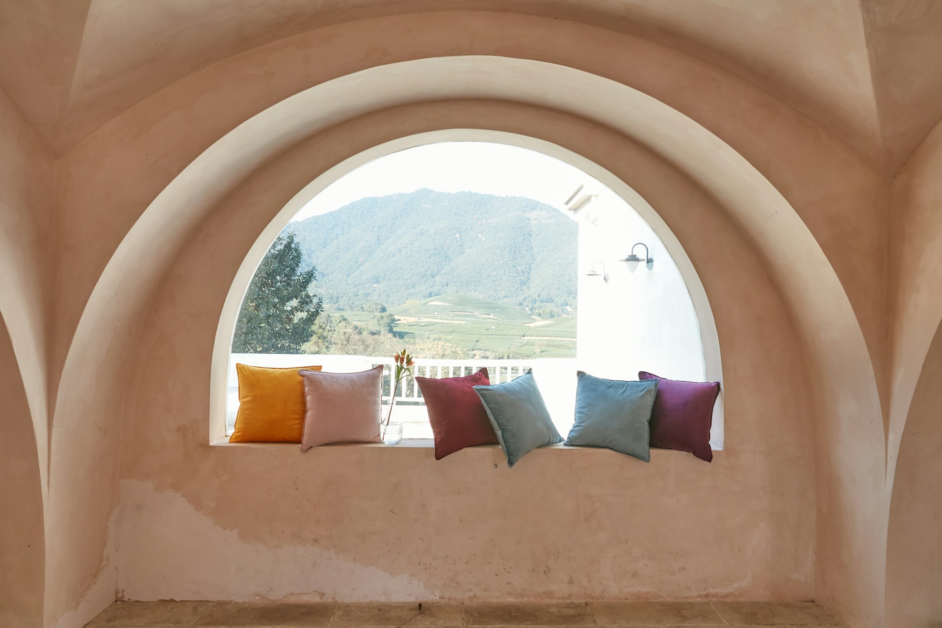 A spacious guest room bathed in soft orange hues, with rounded furniture edges and large windows framing a tranquil desert landscape.
