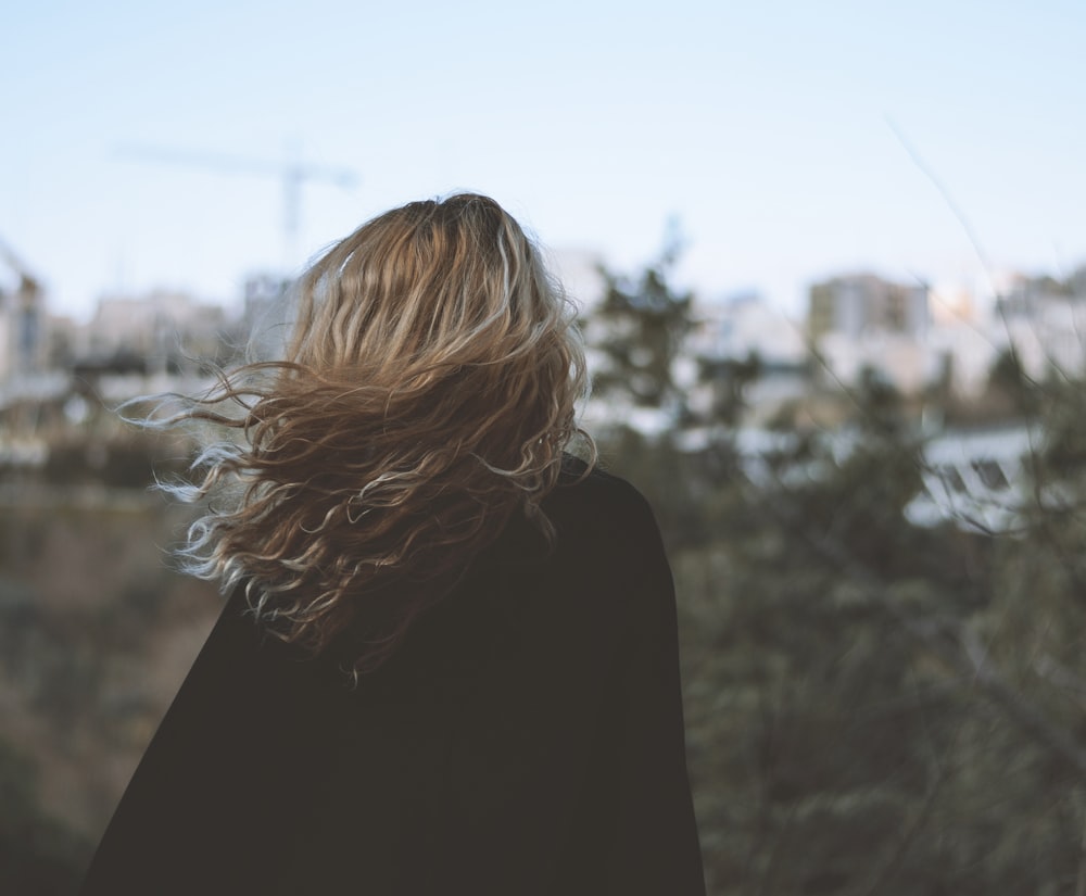 woman in black coat standing on field during daytime