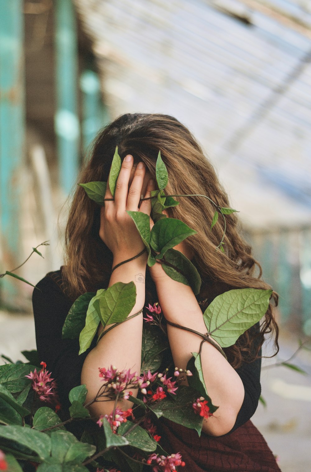 Femme en soutien-gorge floral noir et rose couvrant son visage avec ses cheveux