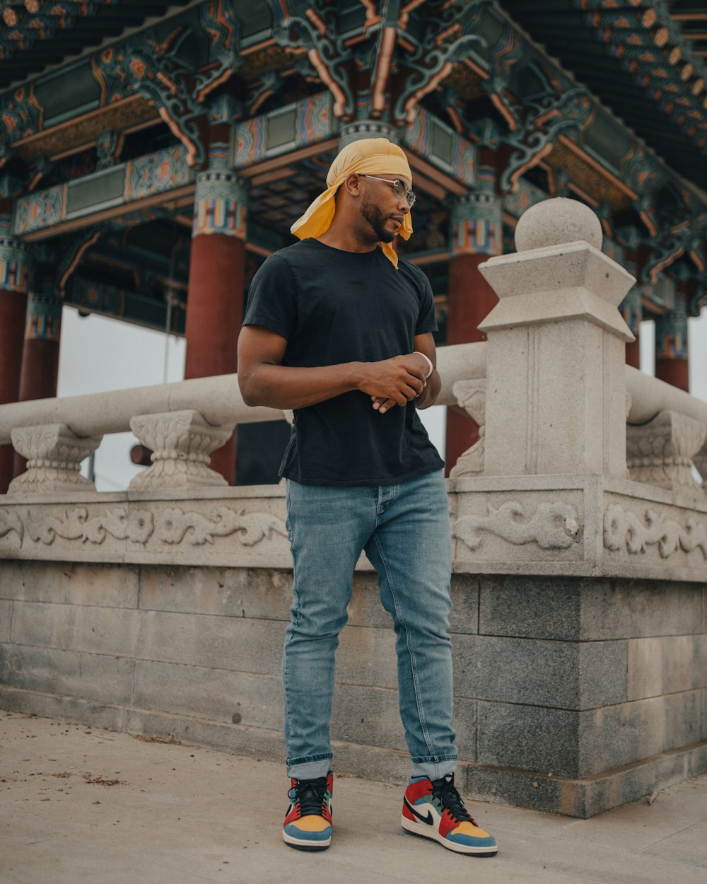 man in black t-shirt and blue denim jeans standing on gray concrete stairs during daytime