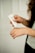 A person is applying a cream or lotion from a tube labeled G&H onto their hand. The focus is on the hands and the tube, with a neutral, soft background. The person has long, curly hair visible in the corner.