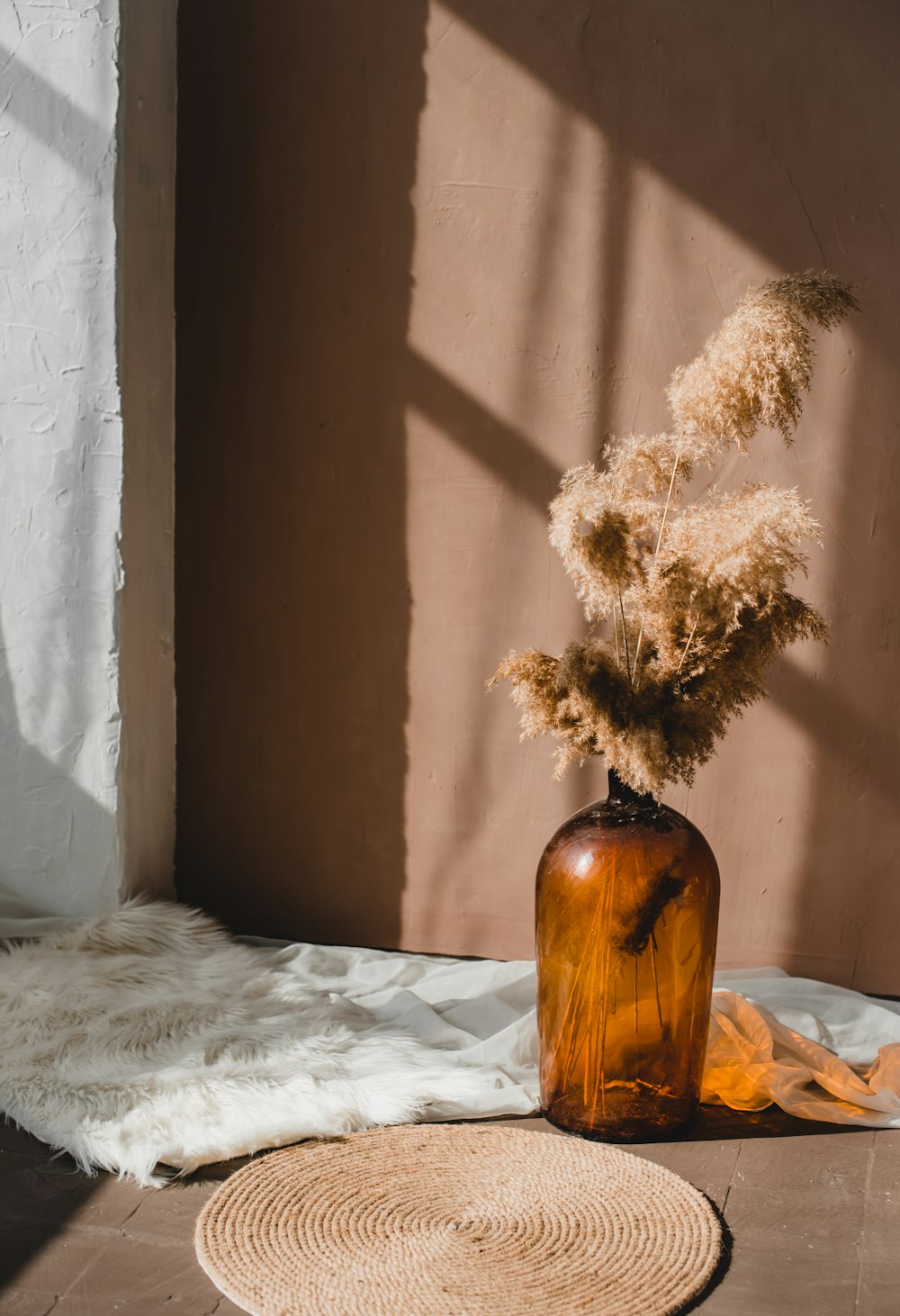 white flowers in brown glass vase on white textile