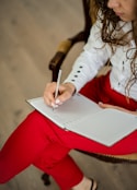 woman in white long sleeve shirt writing on white paper