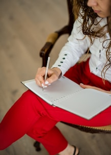woman in white long sleeve shirt writing on white paper