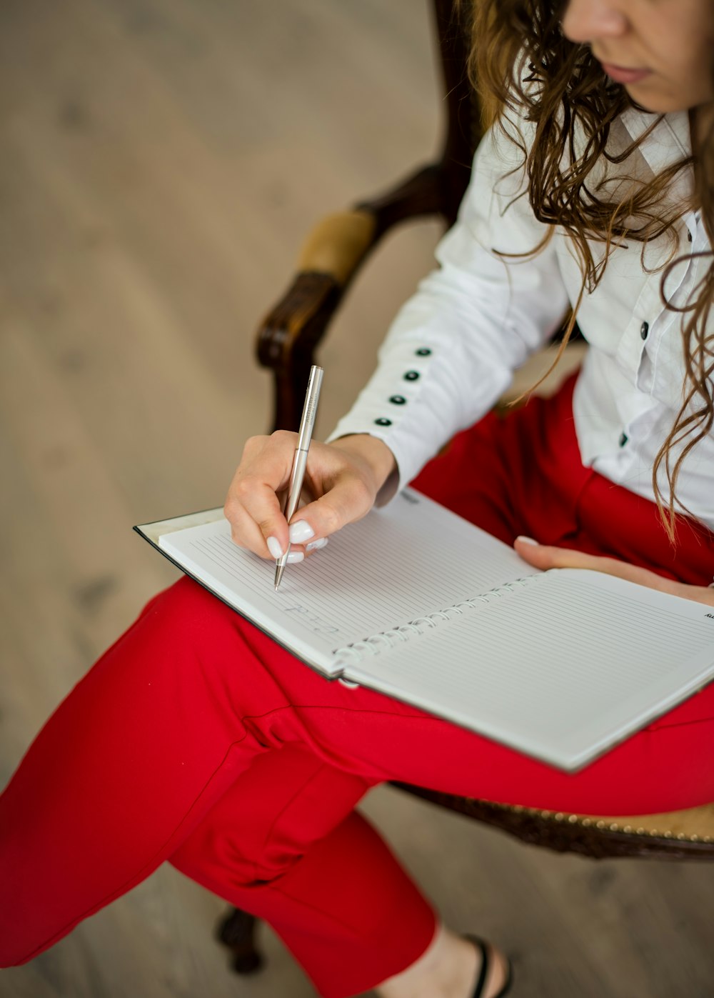 Mujer en camisa blanca de manga larga escribiendo en papel blanco