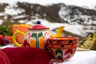 red and yellow ceramic teapot on red textile