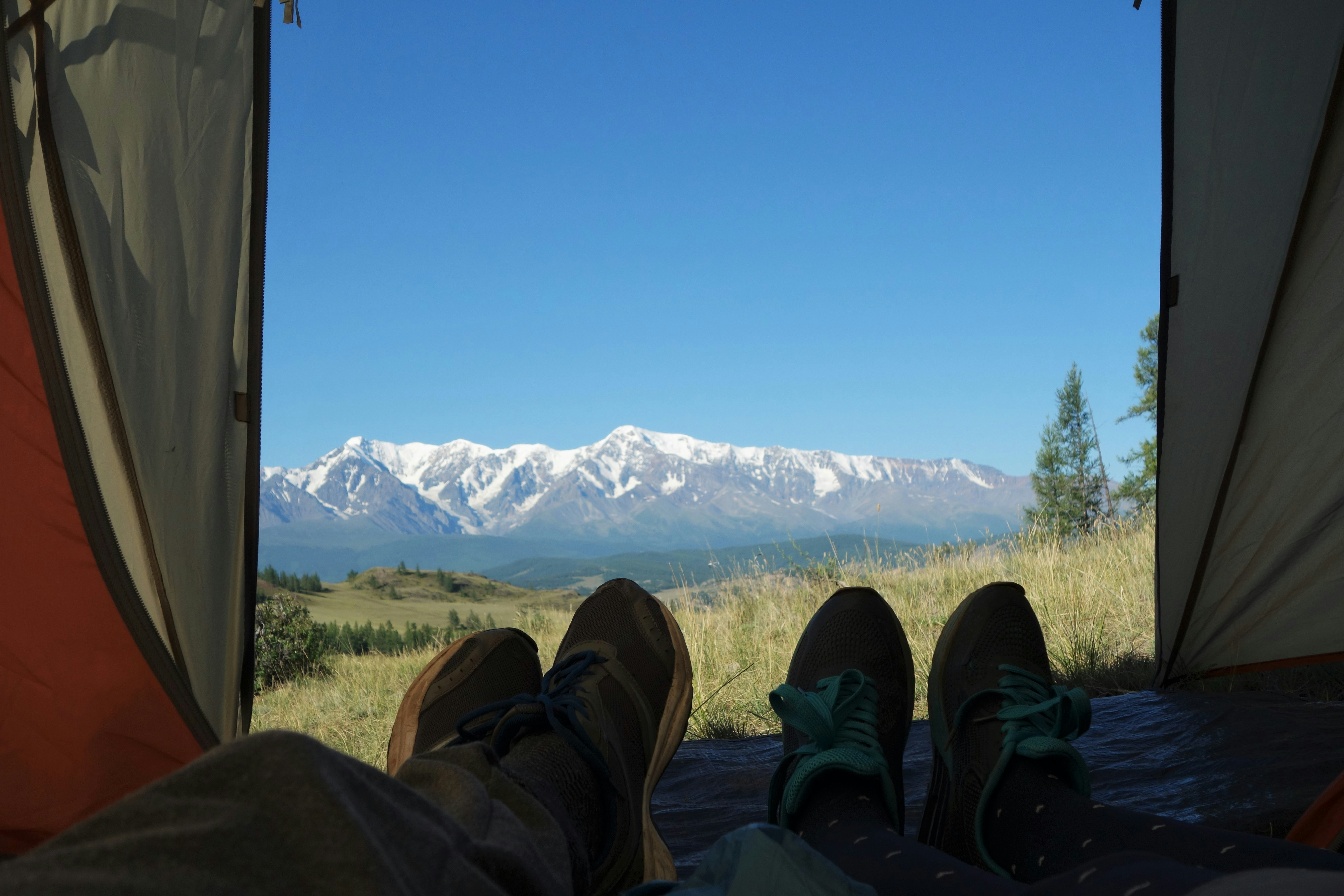 person in black pants and black shoes sitting on brown textile, Camping at Altay mountains