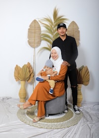 woman in black hijab holding baby in white onesie