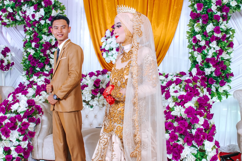 man in brown suit standing beside woman in white floral wedding dress