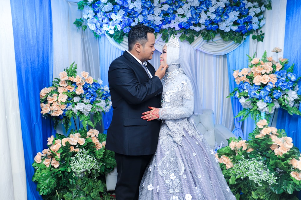 man in black suit kissing woman in white wedding dress