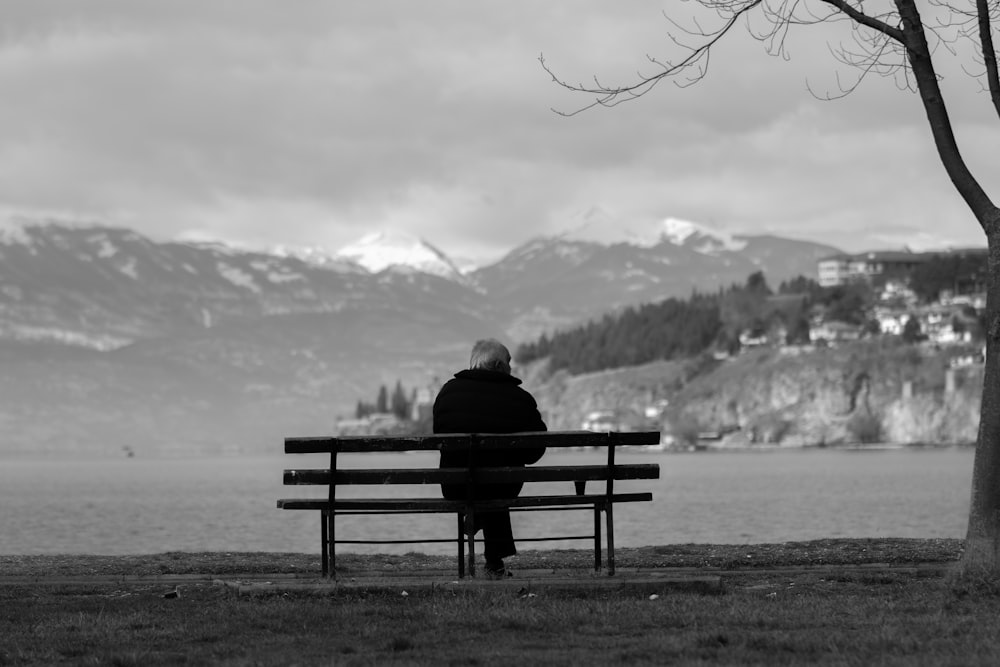 person sitting on bench facing the lake