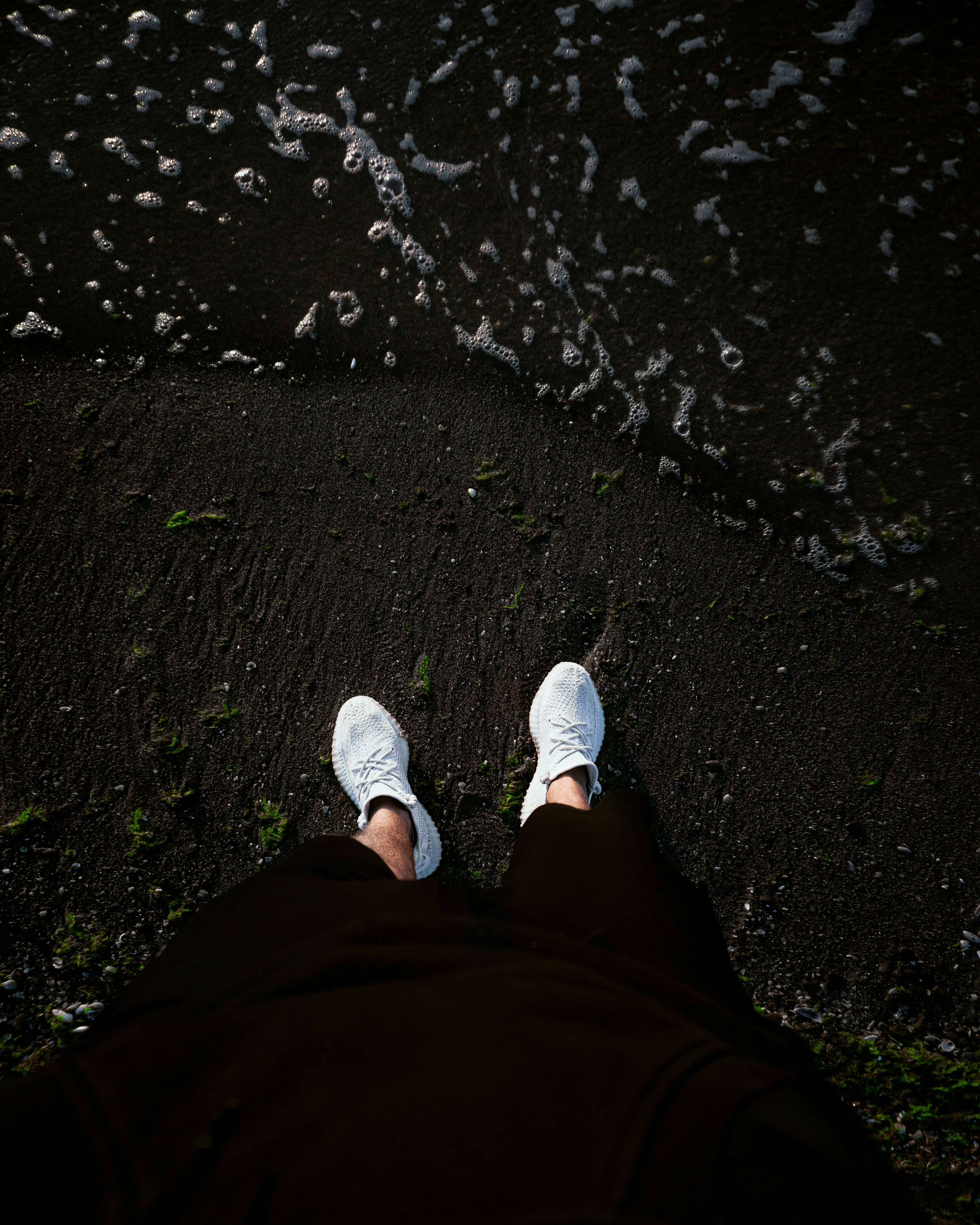 person in black pants and white sneakers standing on rocky ground
