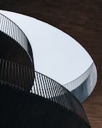 white concrete spiral staircase with brown wooden wall