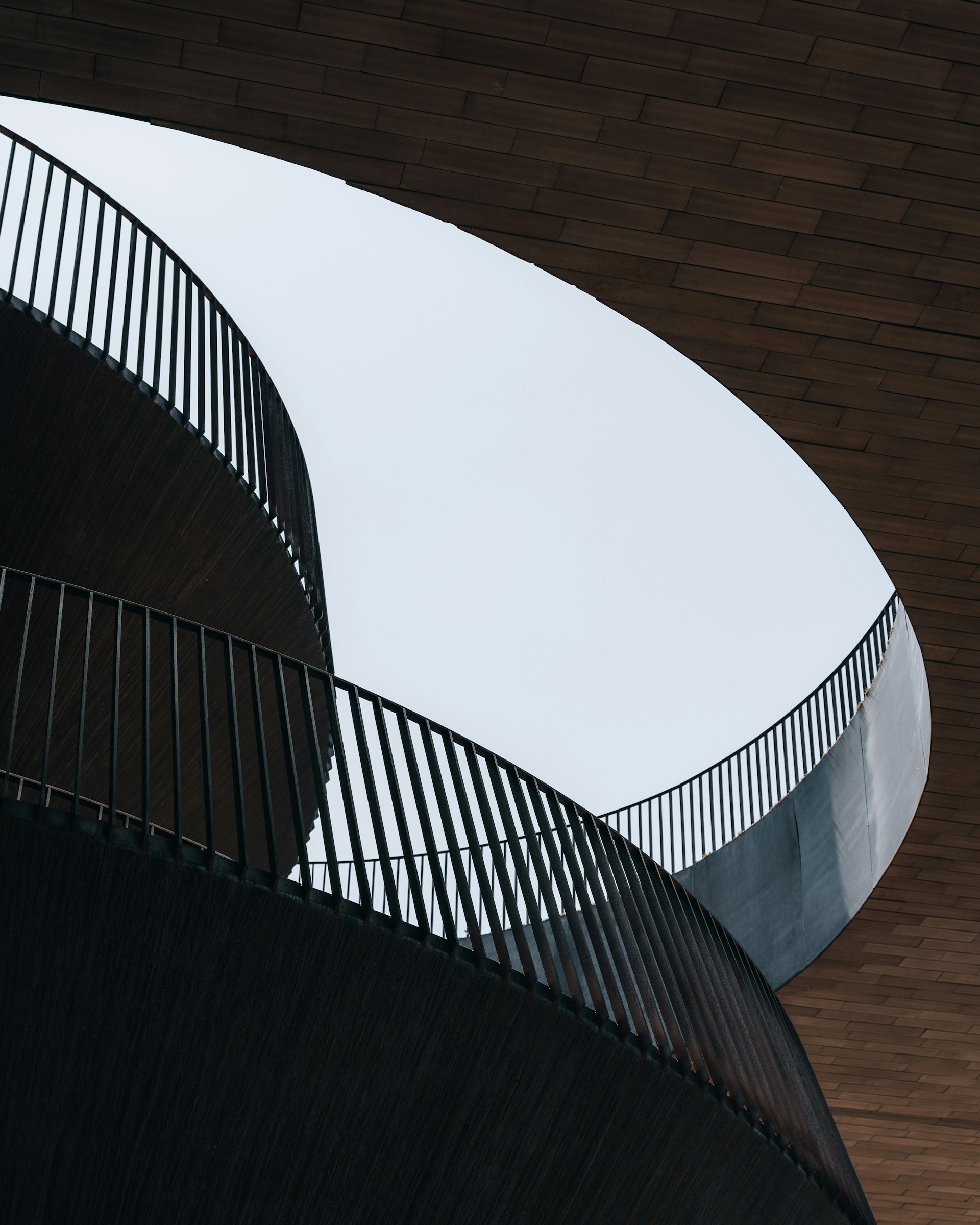 white concrete spiral staircase with brown wooden wall
