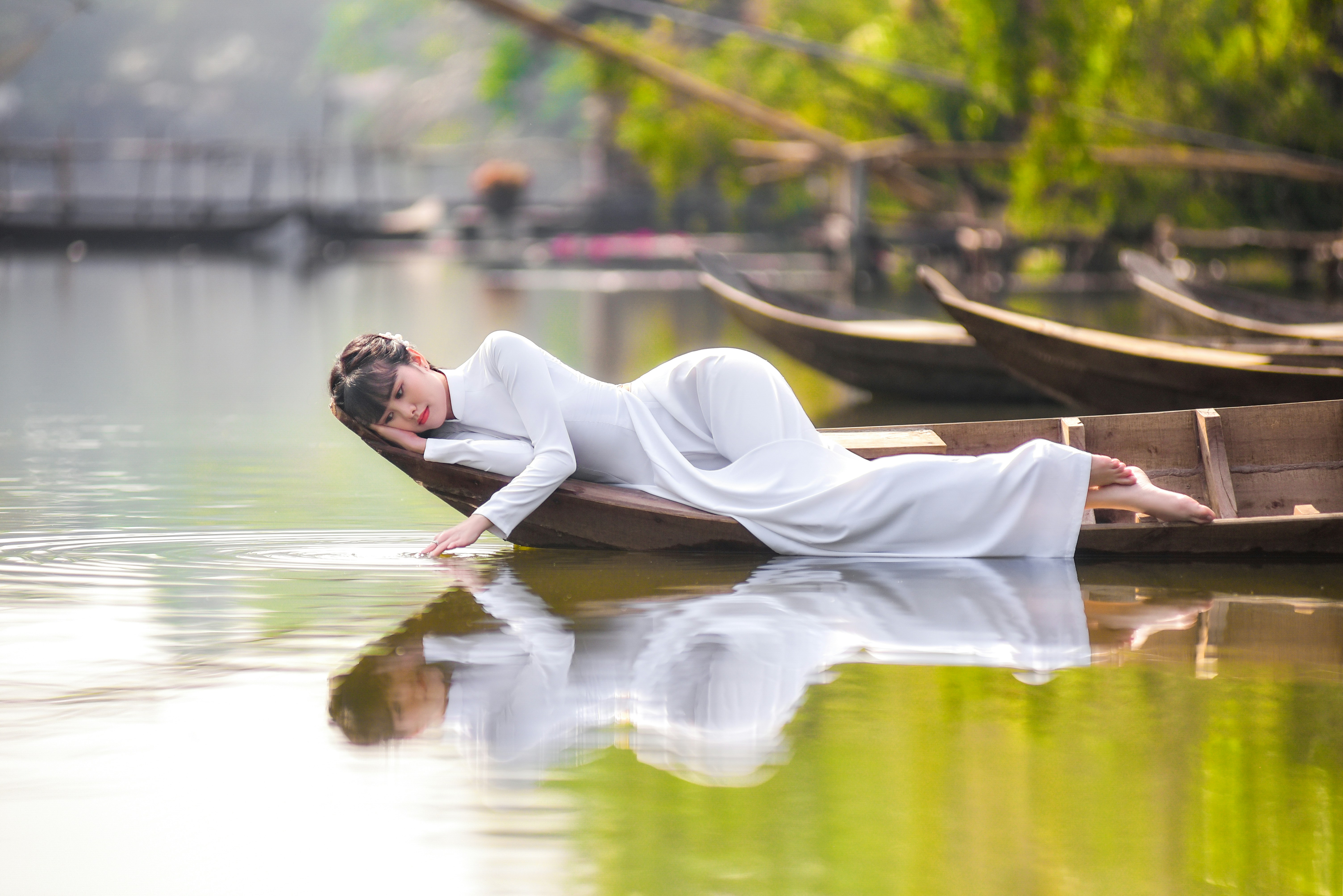 woman in white robe sitting on brown wooden boat on water during daytime