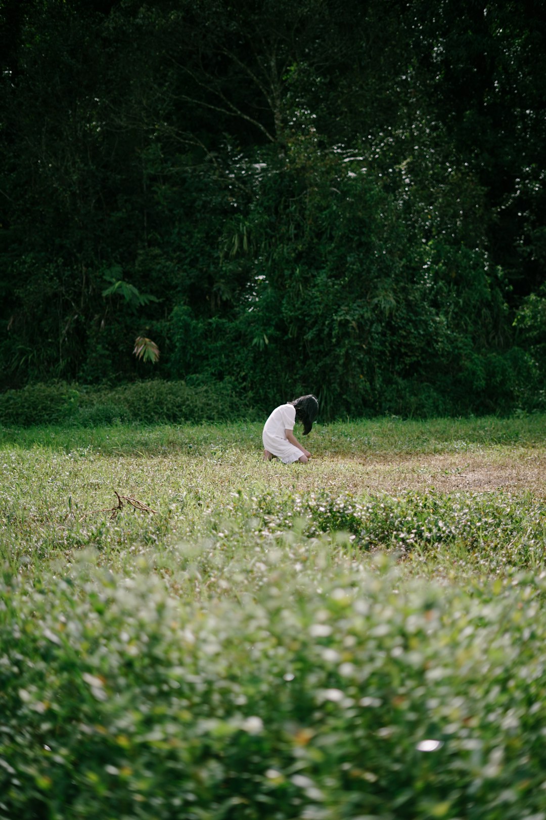 man in white t-shirt sitting on green grass field during daytime