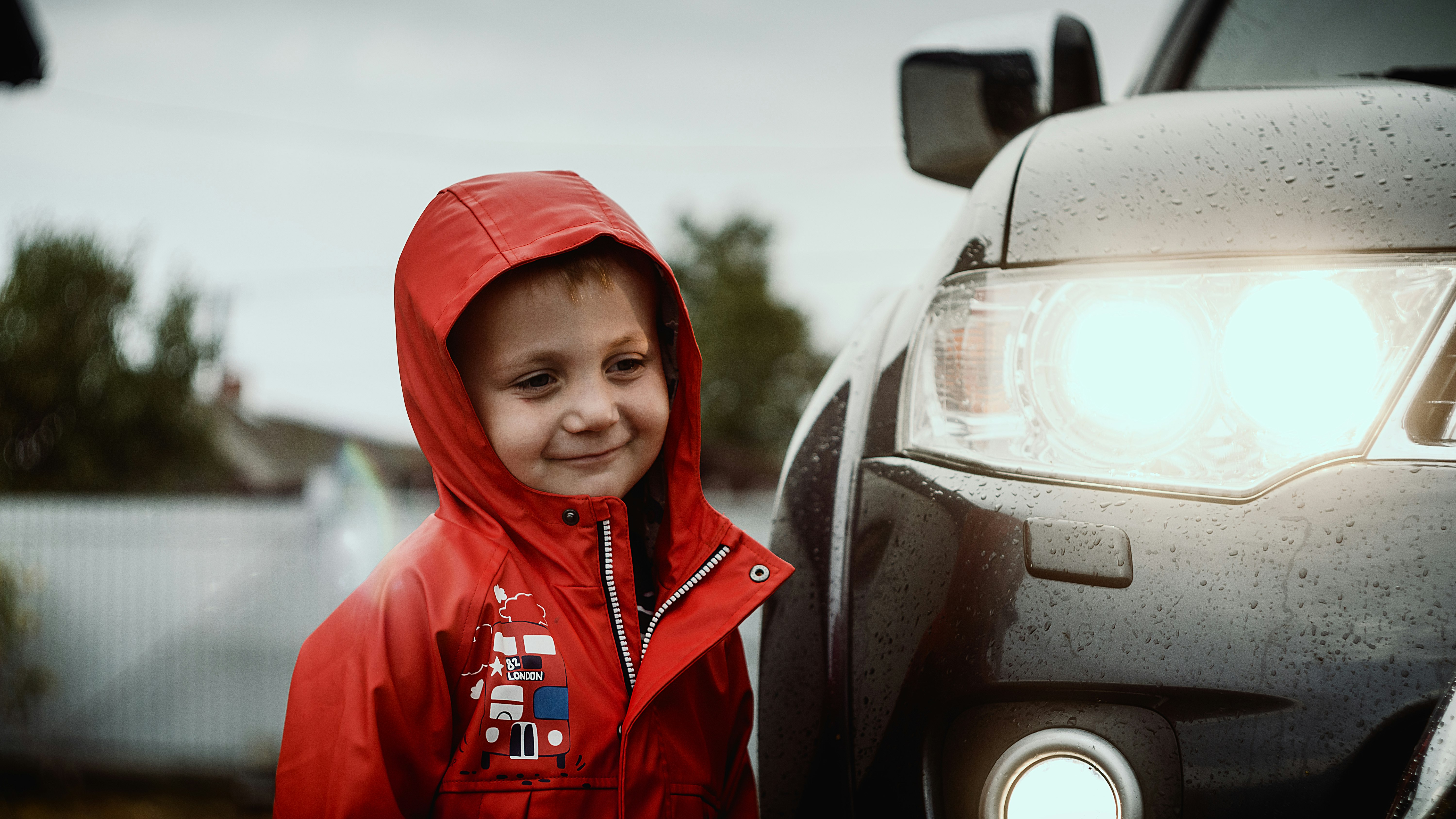 boy in red hoodie standing beside car