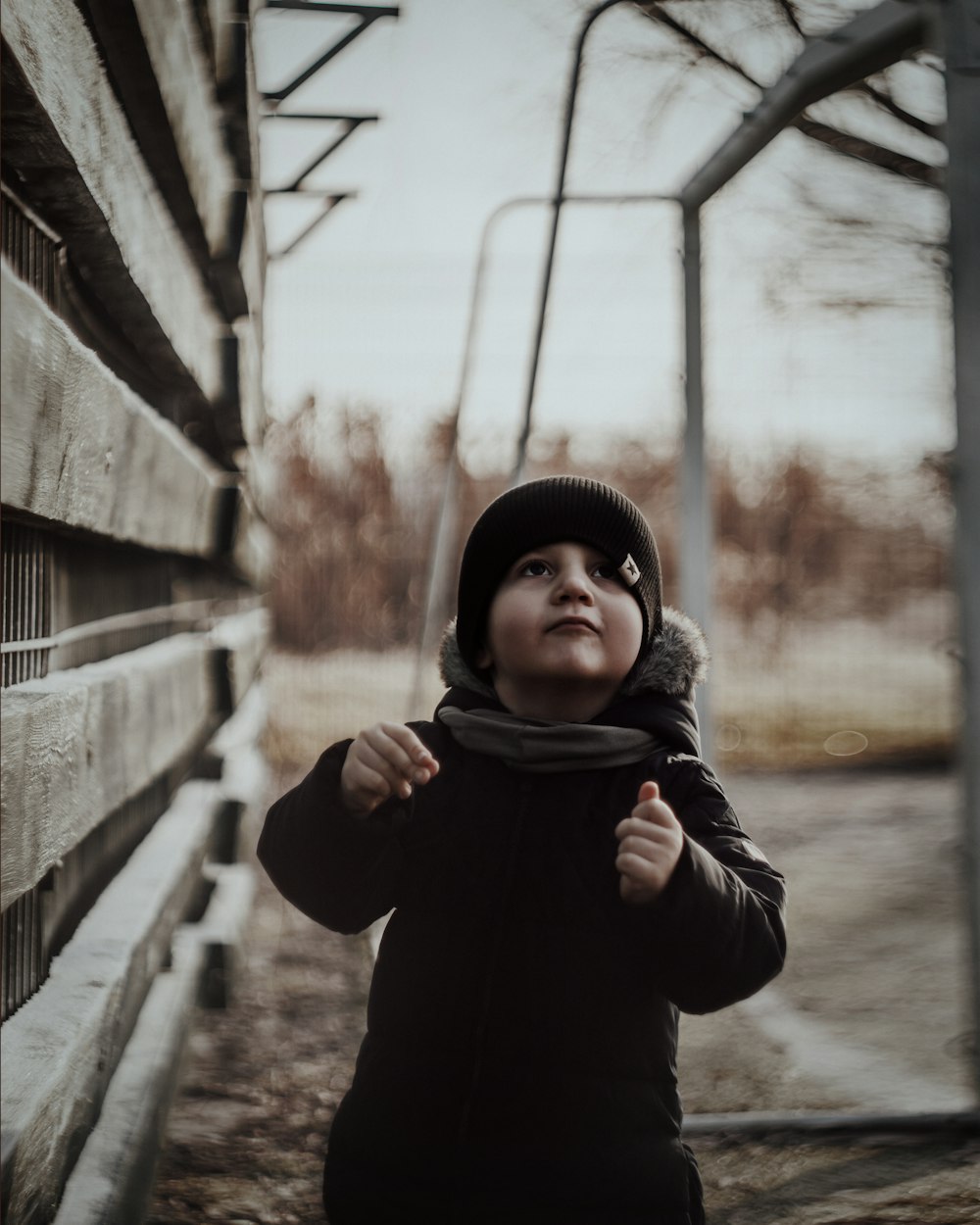 boy in black hoodie standing on bridge during daytime