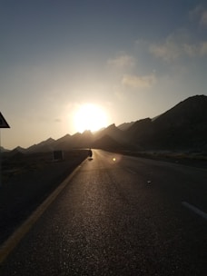 A motorcyclist riding through a dramatic landscape at sunset.