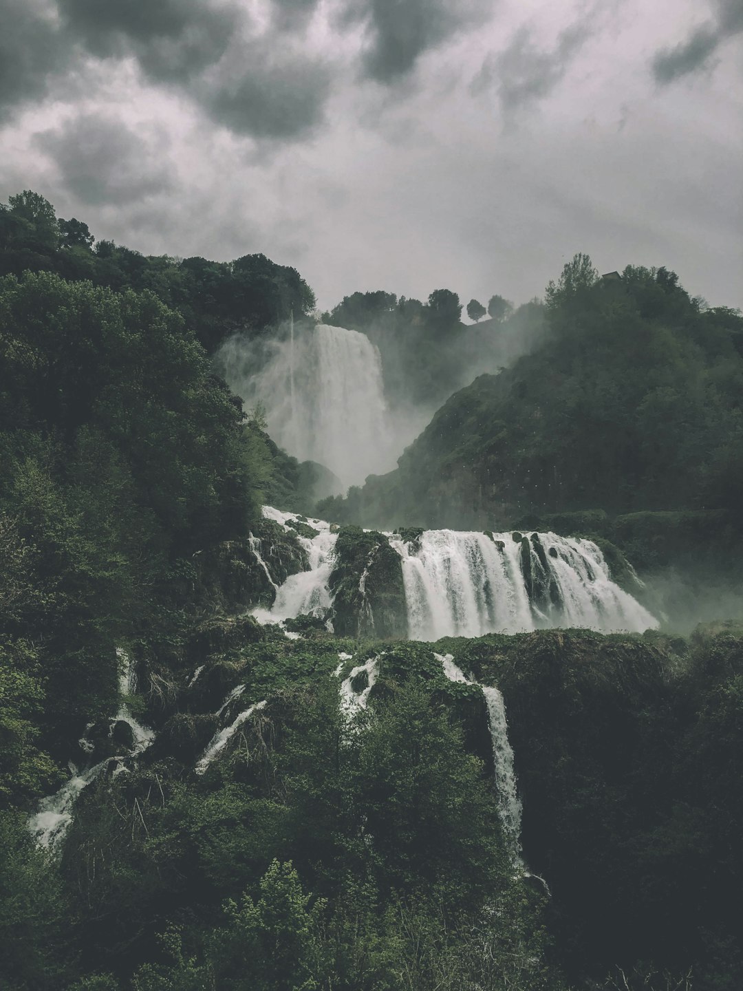 waterfalls in the middle of green trees