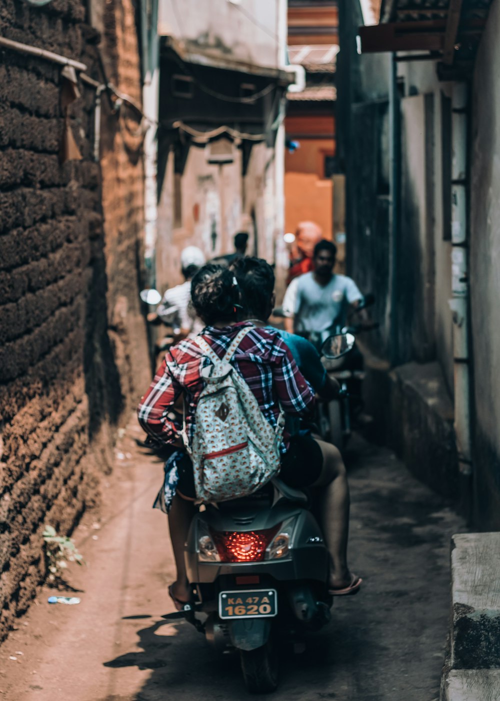 man in red white and blue plaid shirt sitting on black motorcycle during daytime