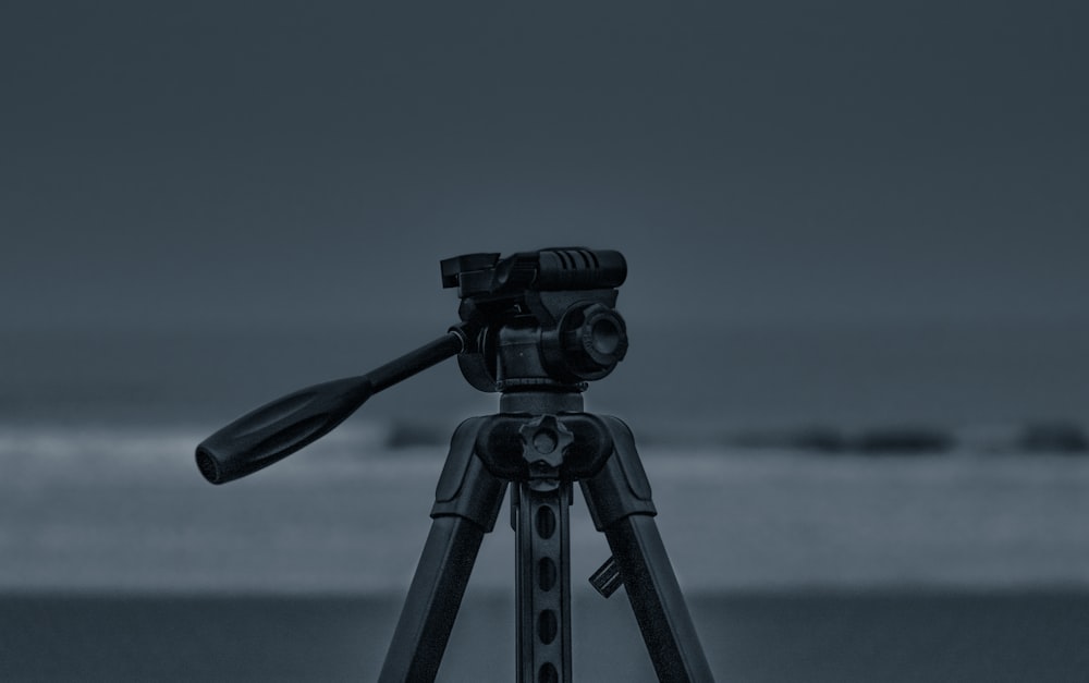 black camera with tripod on the beach