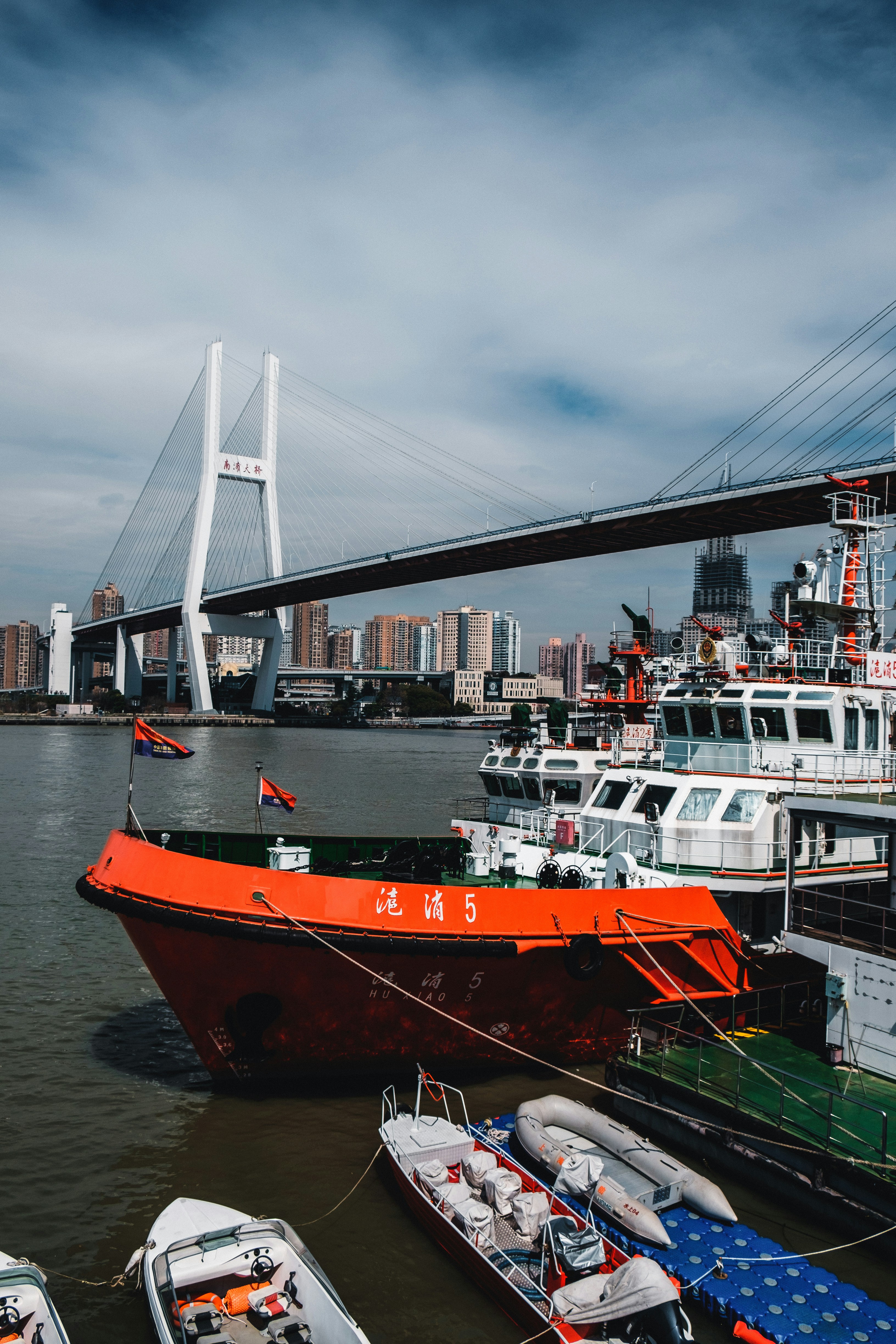 Red and white ship on sea near bridge under white clouds during daytime ...