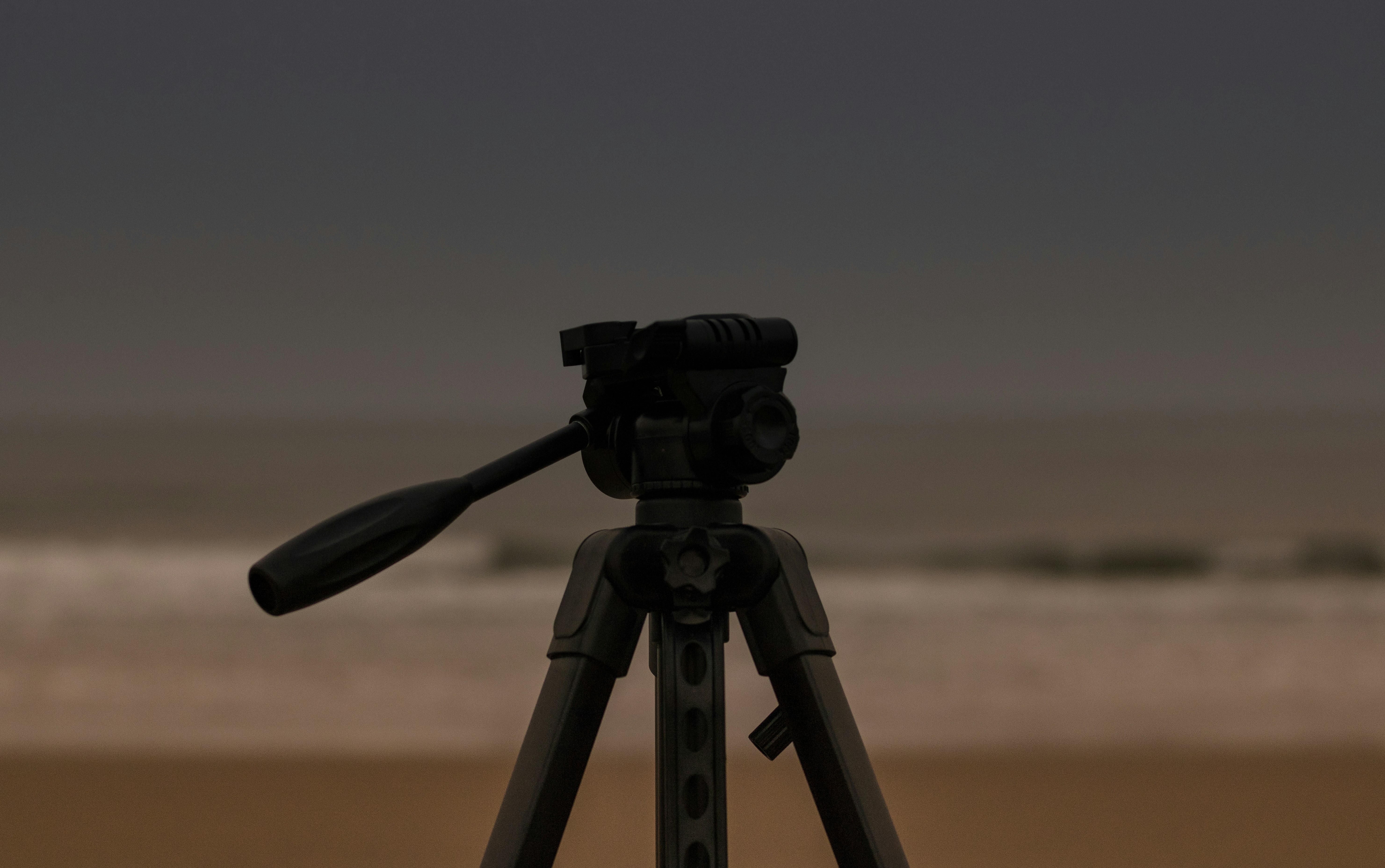 black camera with tripod on brown field during daytime